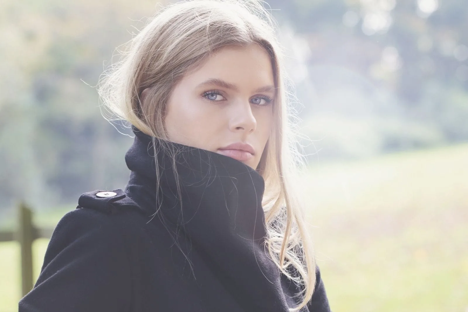 beautiful woman staring at the camera thoughtfully wearing coat standing outdoors