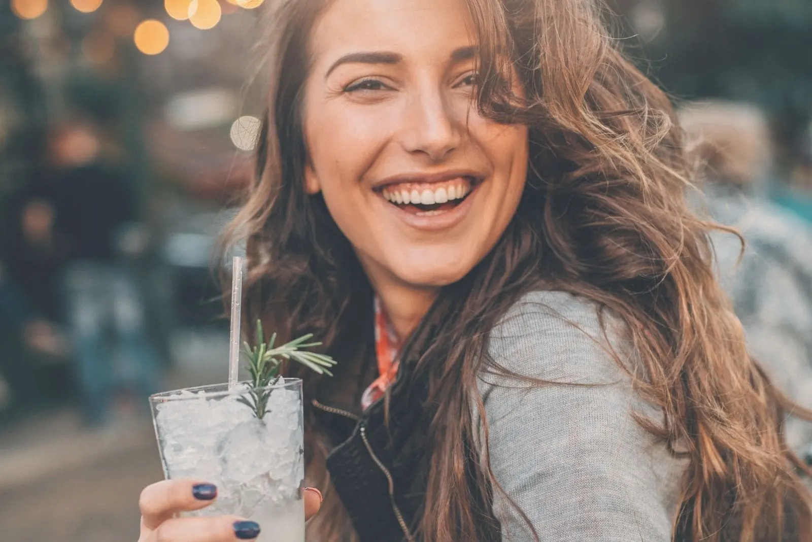 beautiful young woman drinking cocktails and smiling outdoors