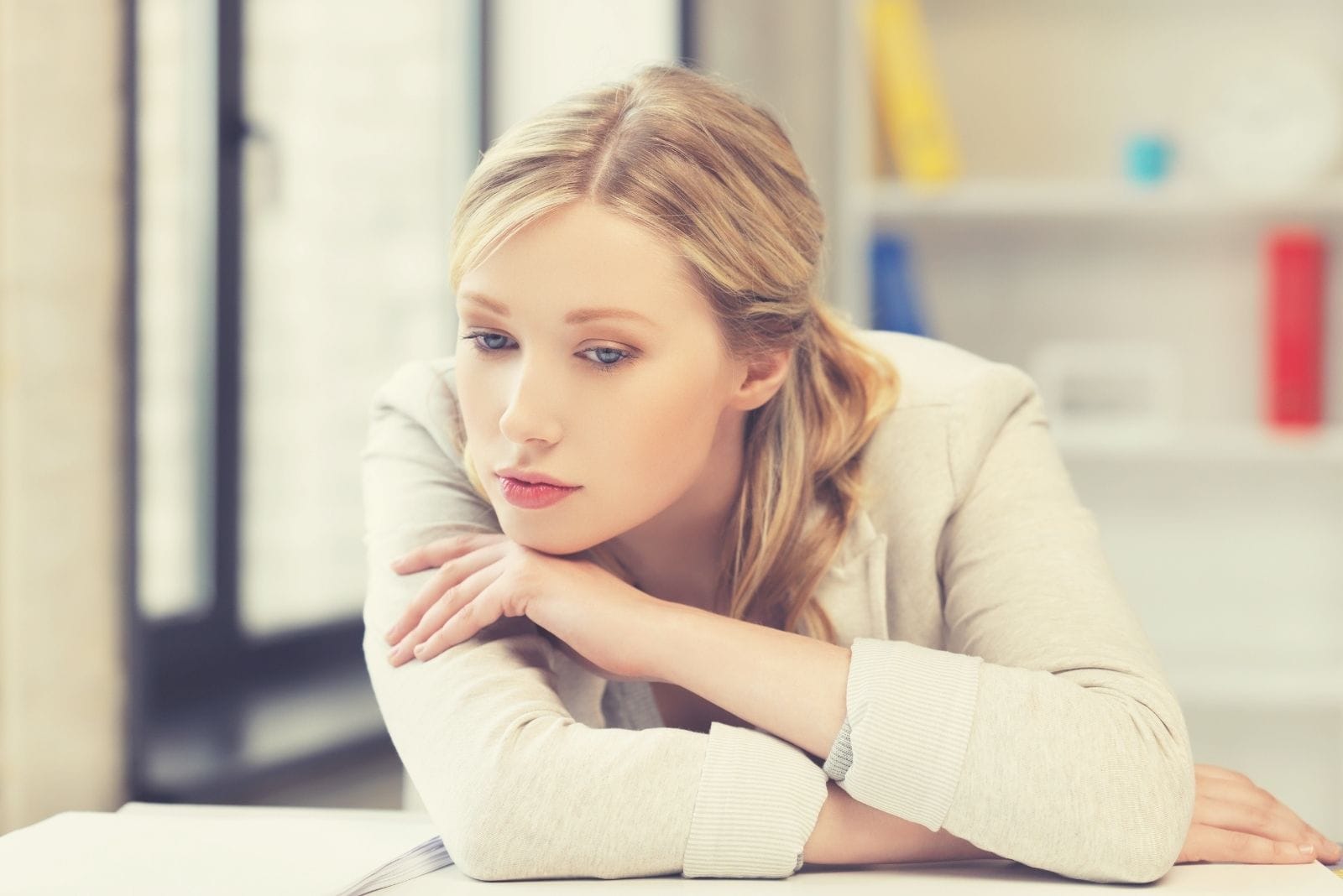 bored and tired woman leaning on the table near the windows of her office