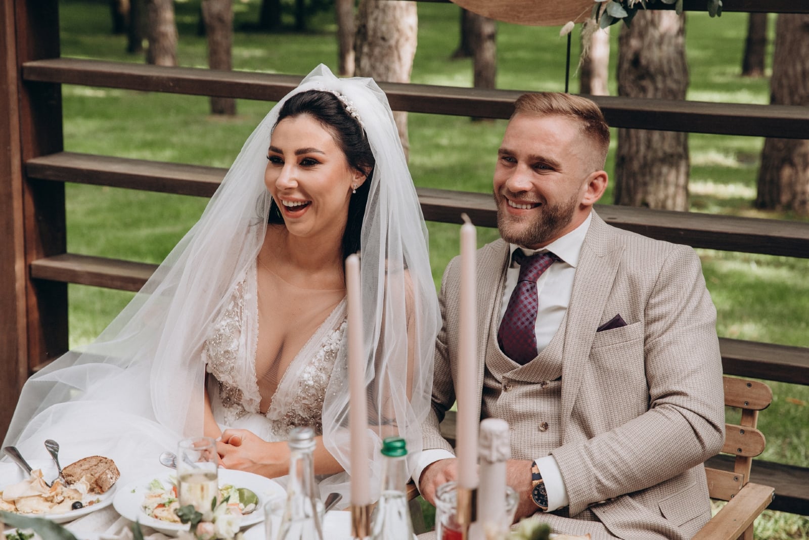 bride and groom smiling while sitting at wedding table