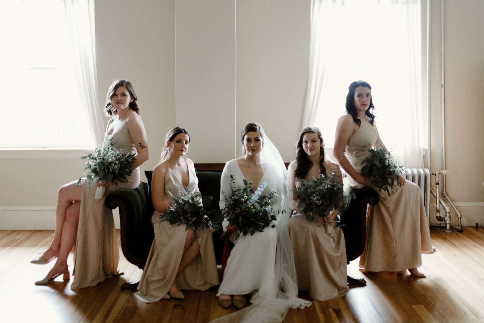 novia y damas de honor sentadas en un sofá sosteniendo un ramo de flores