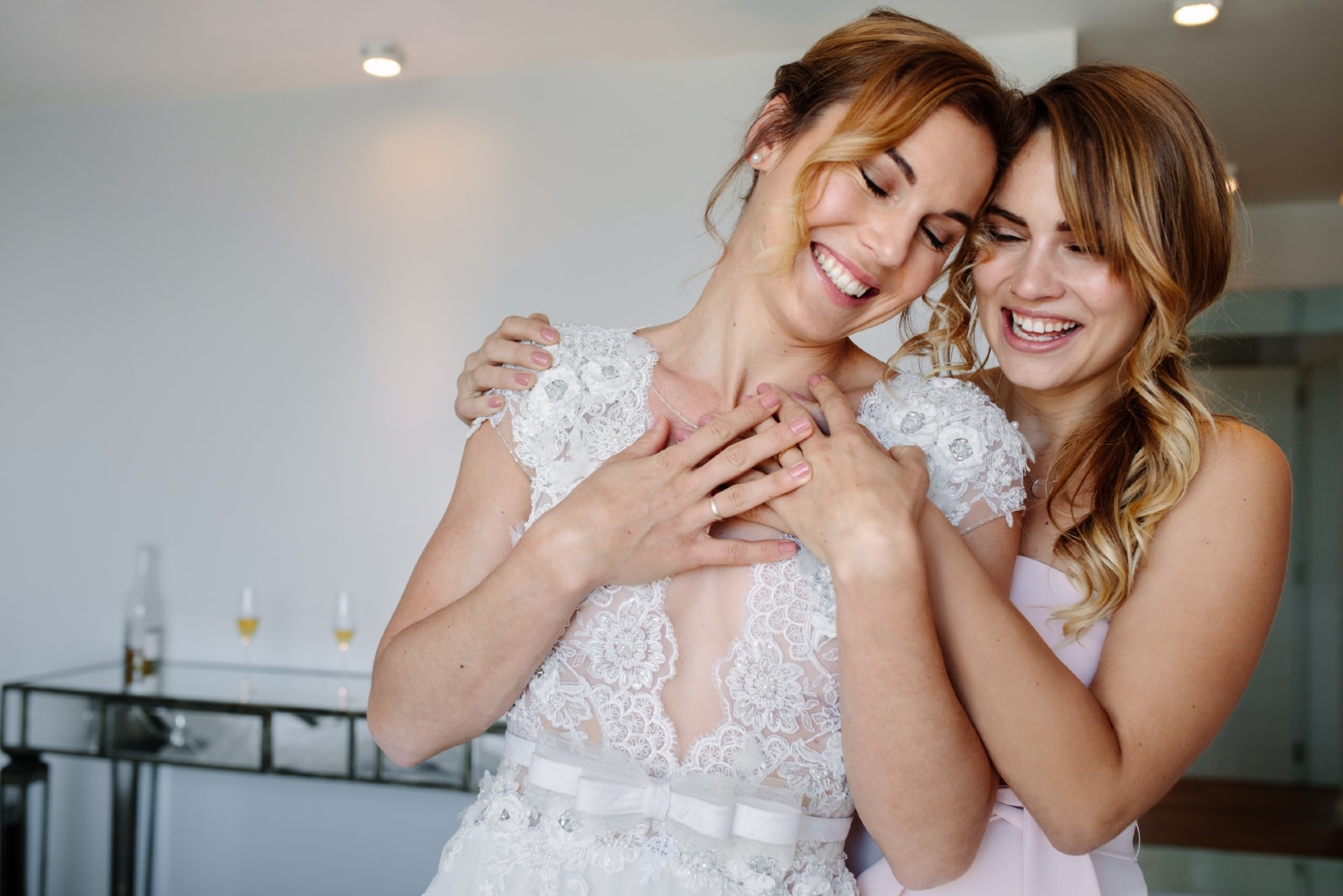 happy bridesmaid in white dress hugging bride