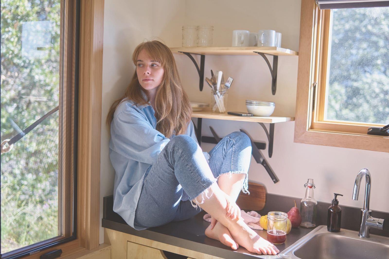 joven tranquila sentada en la encimera de la cocina mirando hacia otro lado