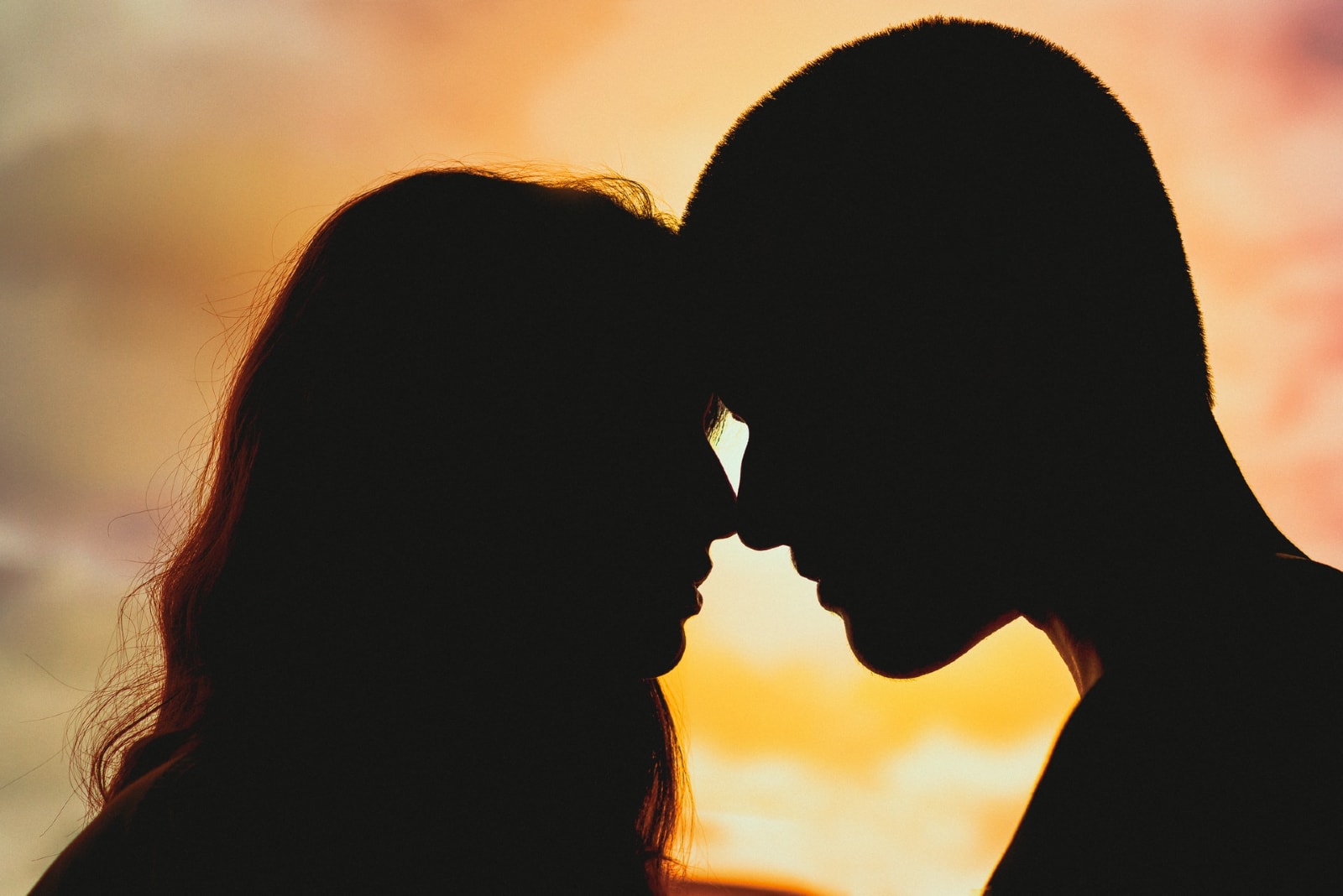 man and woman about to kiss during sunset