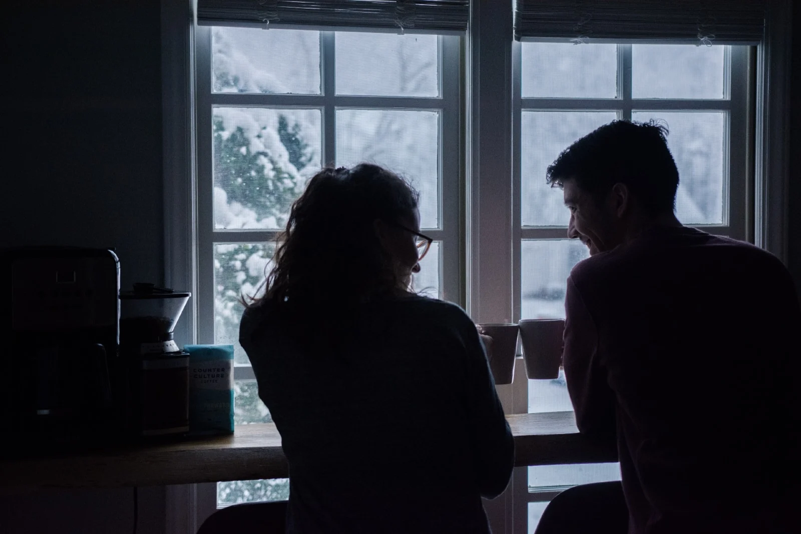 man and woman drinking coffee while sitting near window