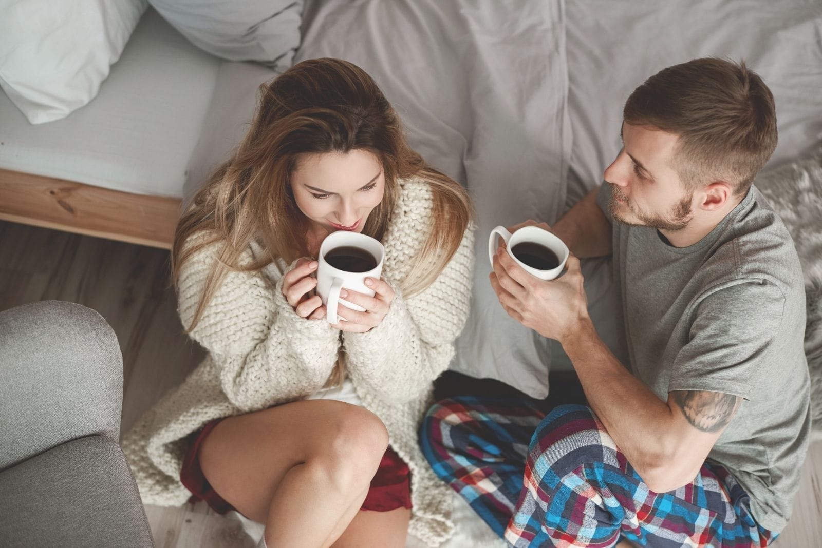 couple drinking morning coffee beside the bed on the floor