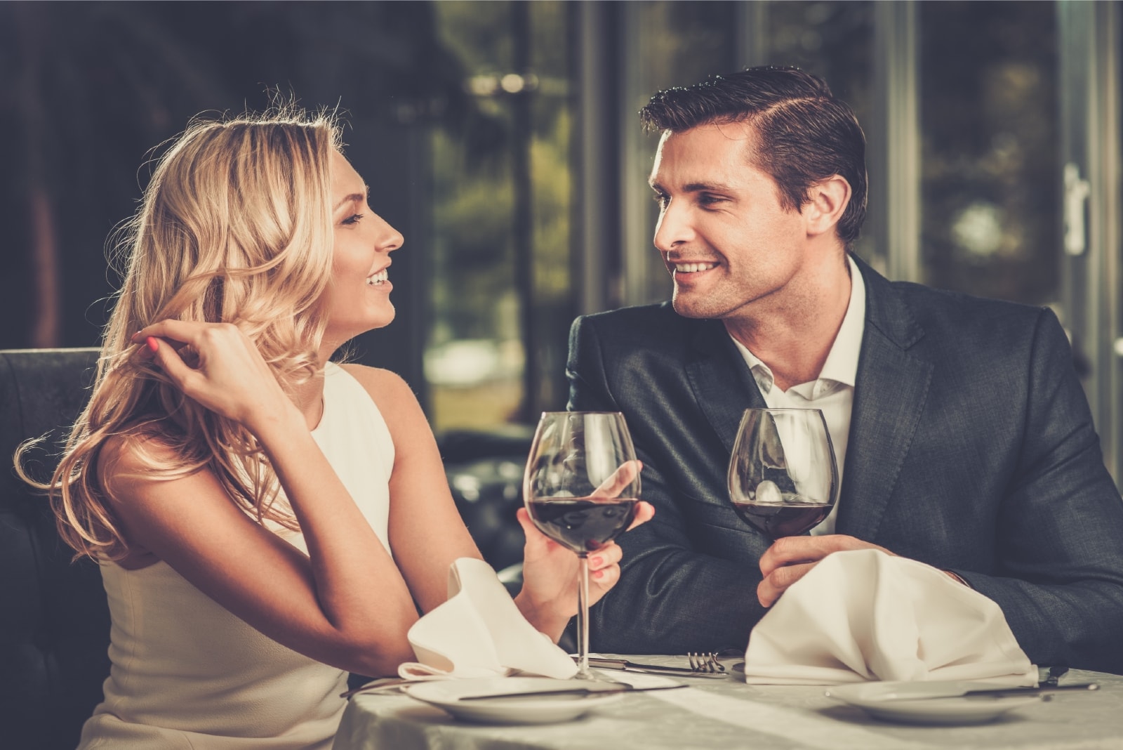 hombre y mujer felices bebiendo vino sentados a la mesa