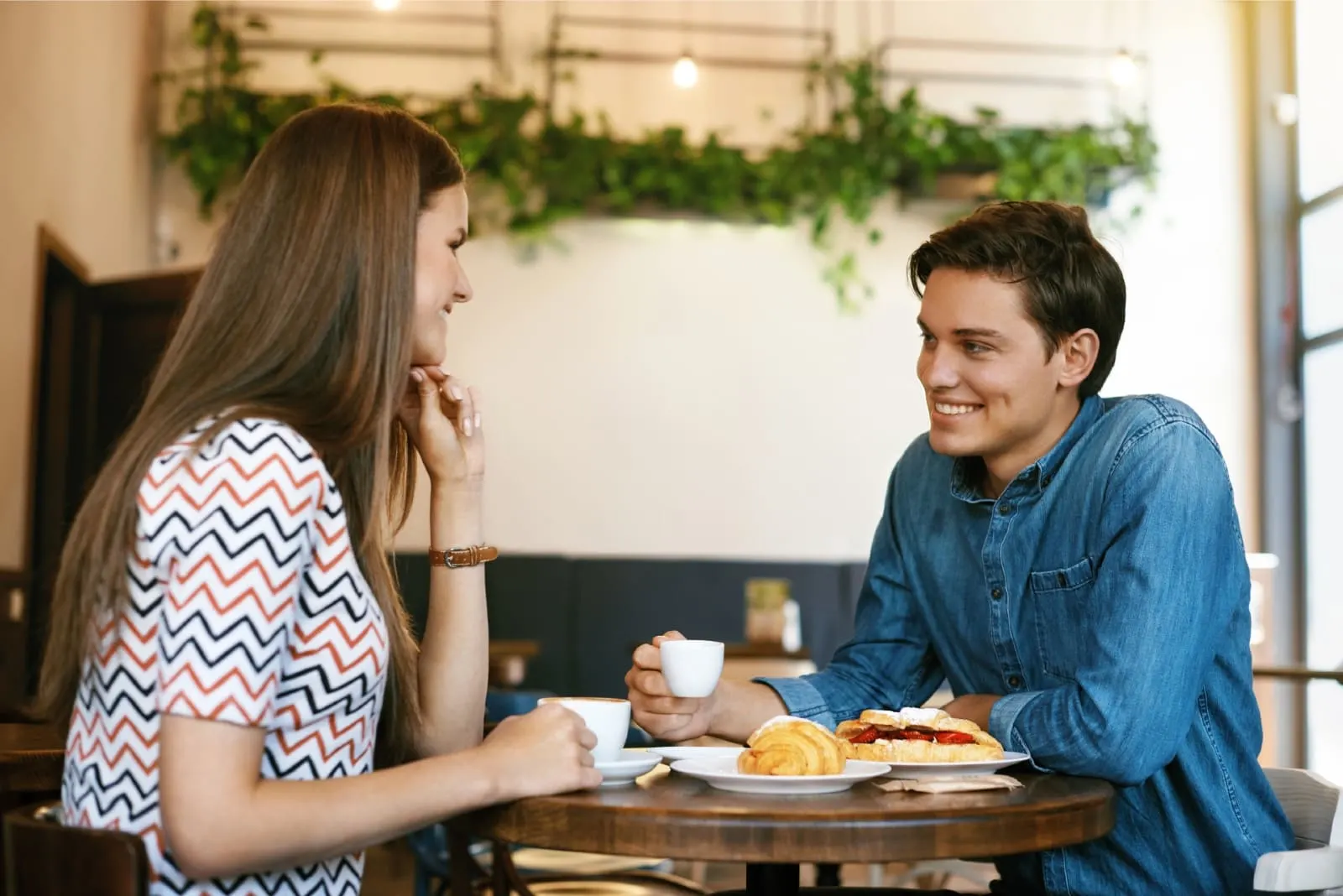 man and woman having coffee while sitting in cafe