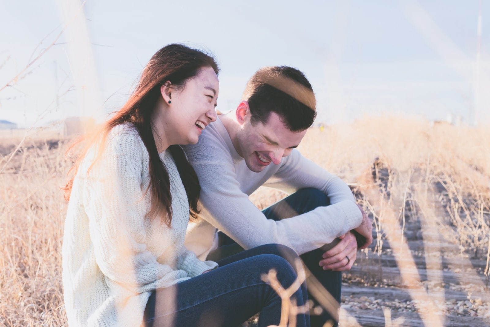 man and woman laughing while sitting by the tracks