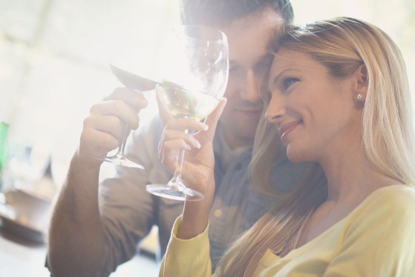 coppia ad un appuntamento romantico che alza e fa tintinnare il proprio vino 
