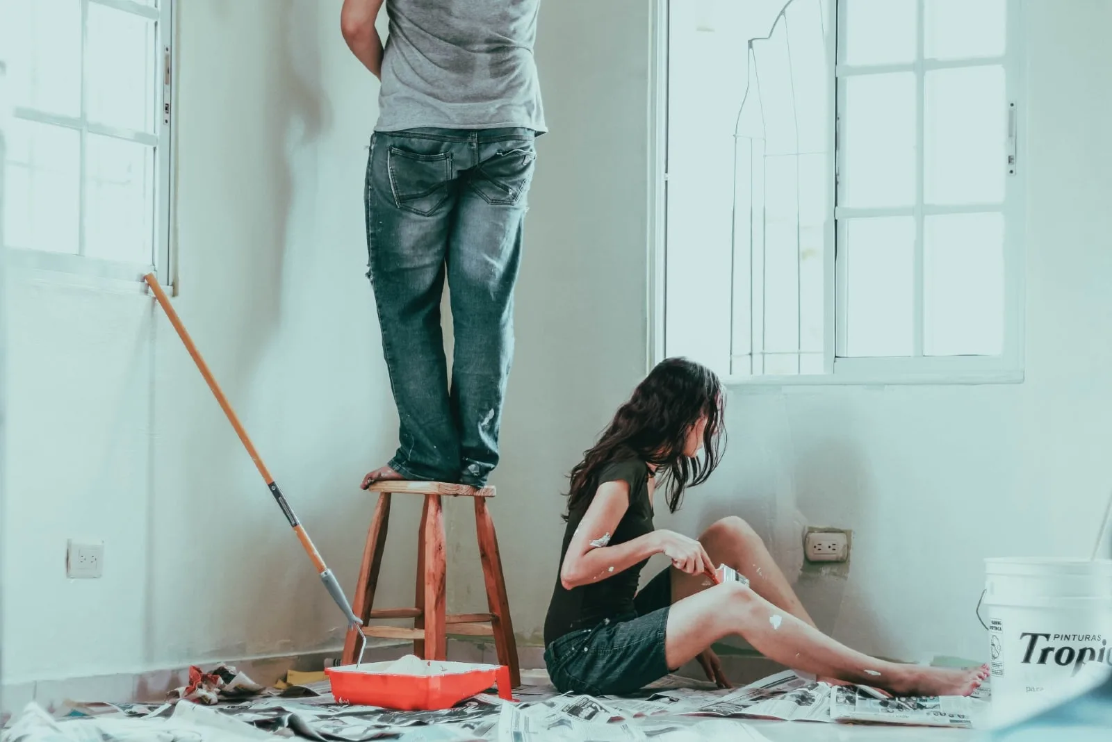 man and woman painting wall during daytime