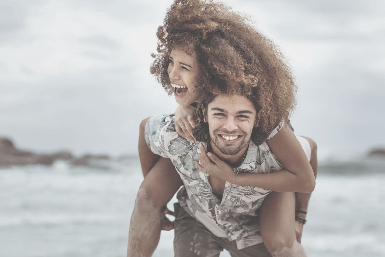 couple piggybacking and laughing near the sea