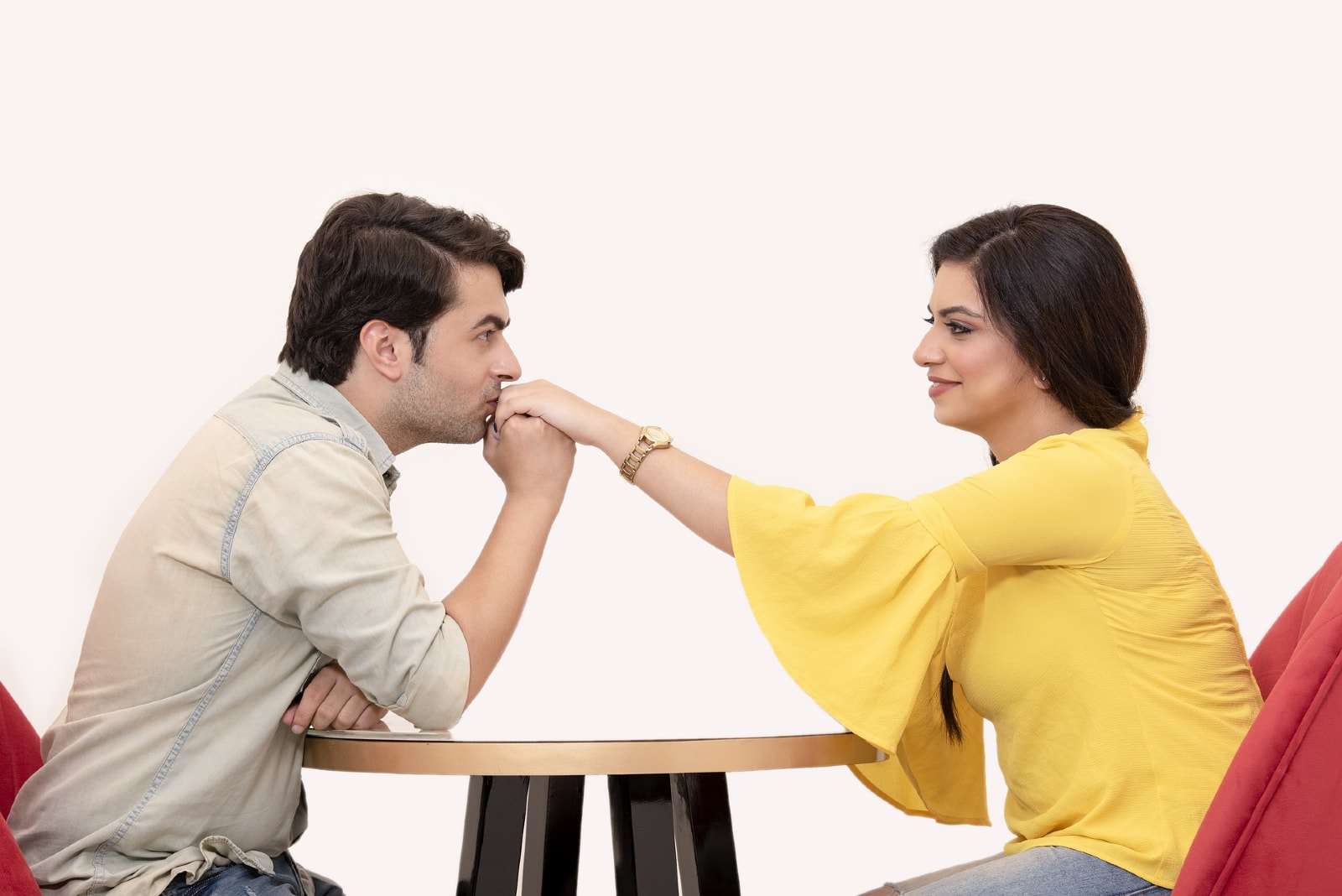 homem a beijar a mão de uma mulher sentada à mesa