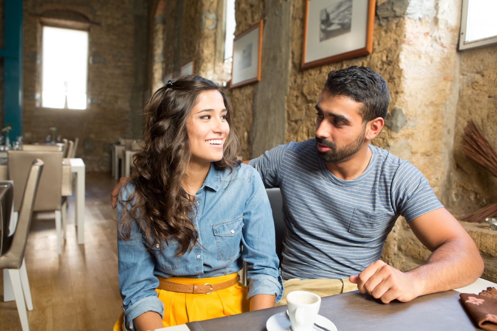 man and woman making eye contact while sitting in cafe