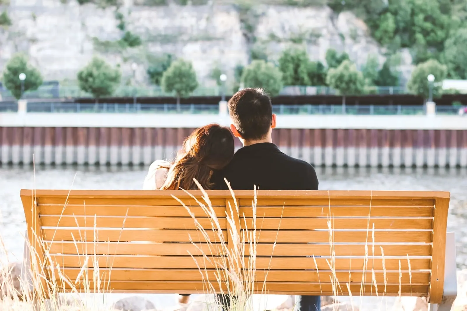 woman leaning on man's shoulder while sitting on bench