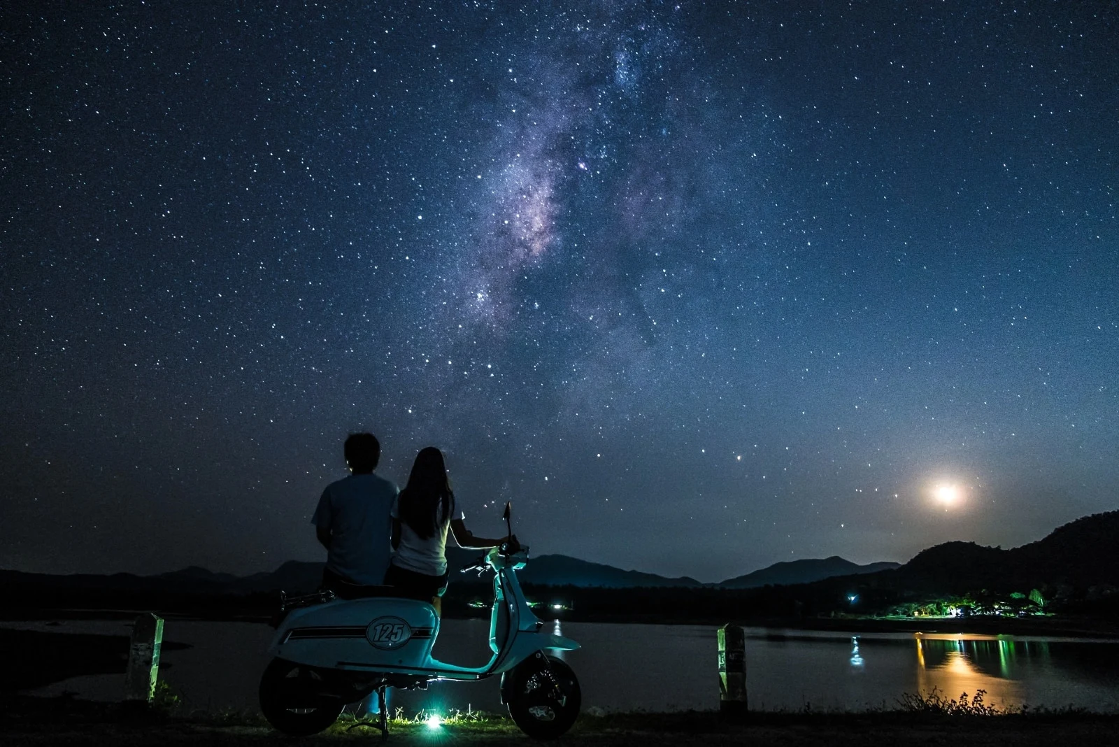 man and woman sitting on motorcycle looking at stars