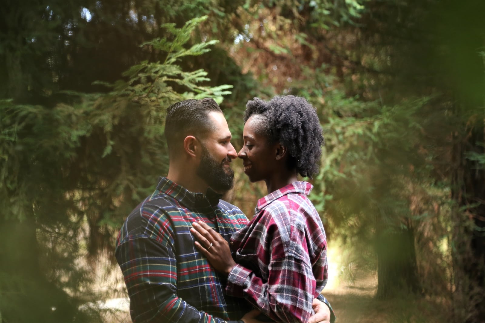 man and woman hugging while standing in forest