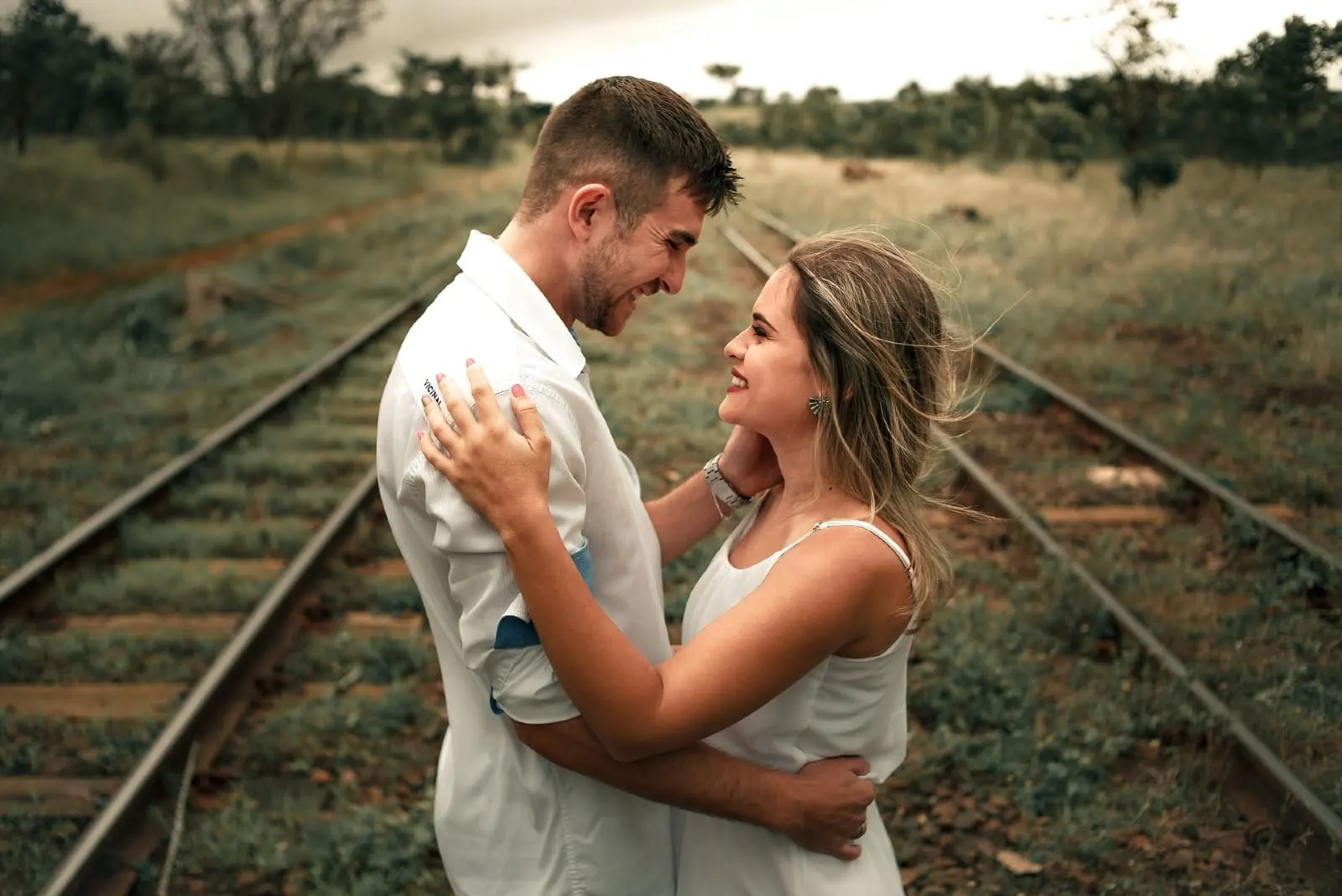 man and woman hugging while standing near railway