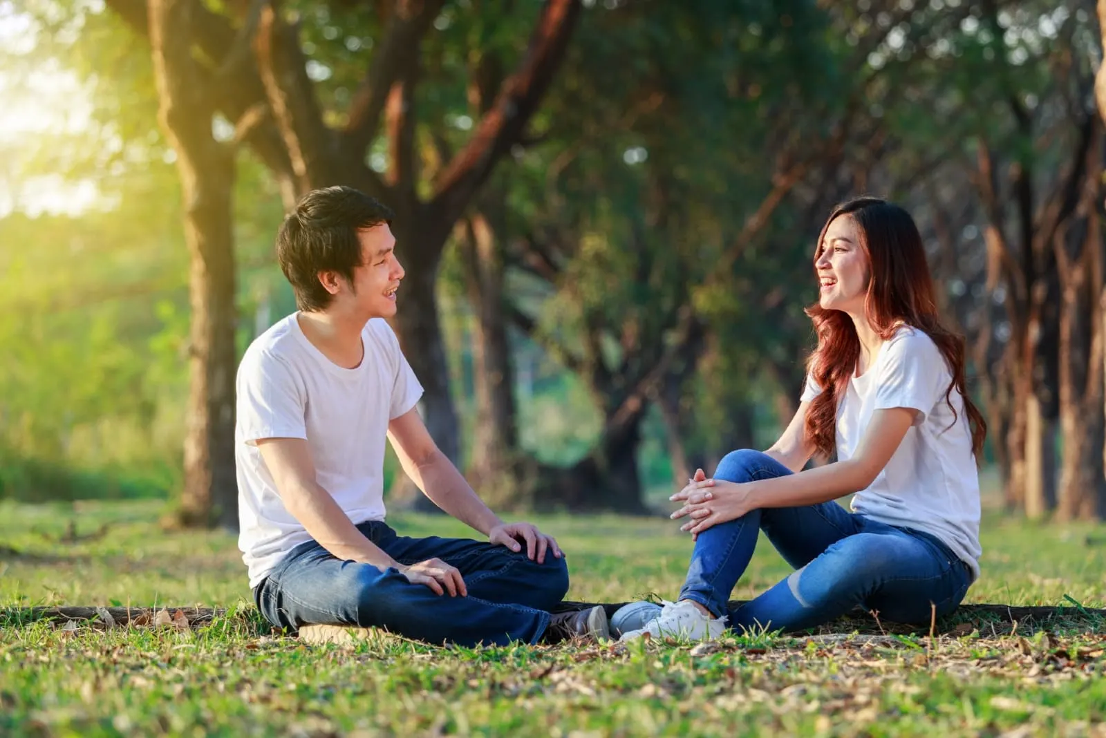 man and woman talking while sitting on grass