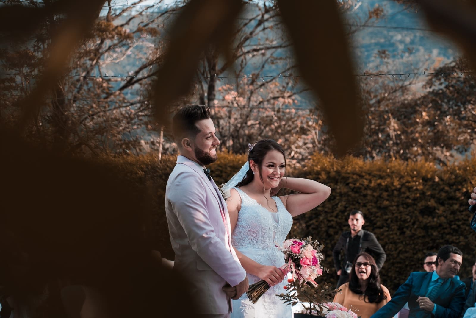 sposo e sposa con bouquet di fiori in piedi all'aperto