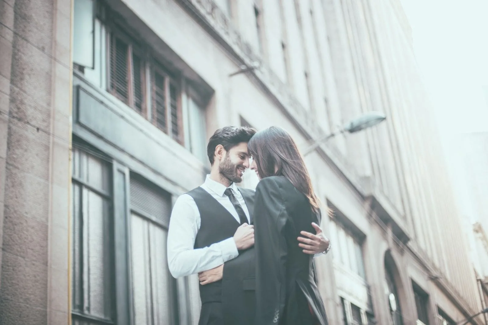 handsome gentleman in suit hugging a woman outdoors