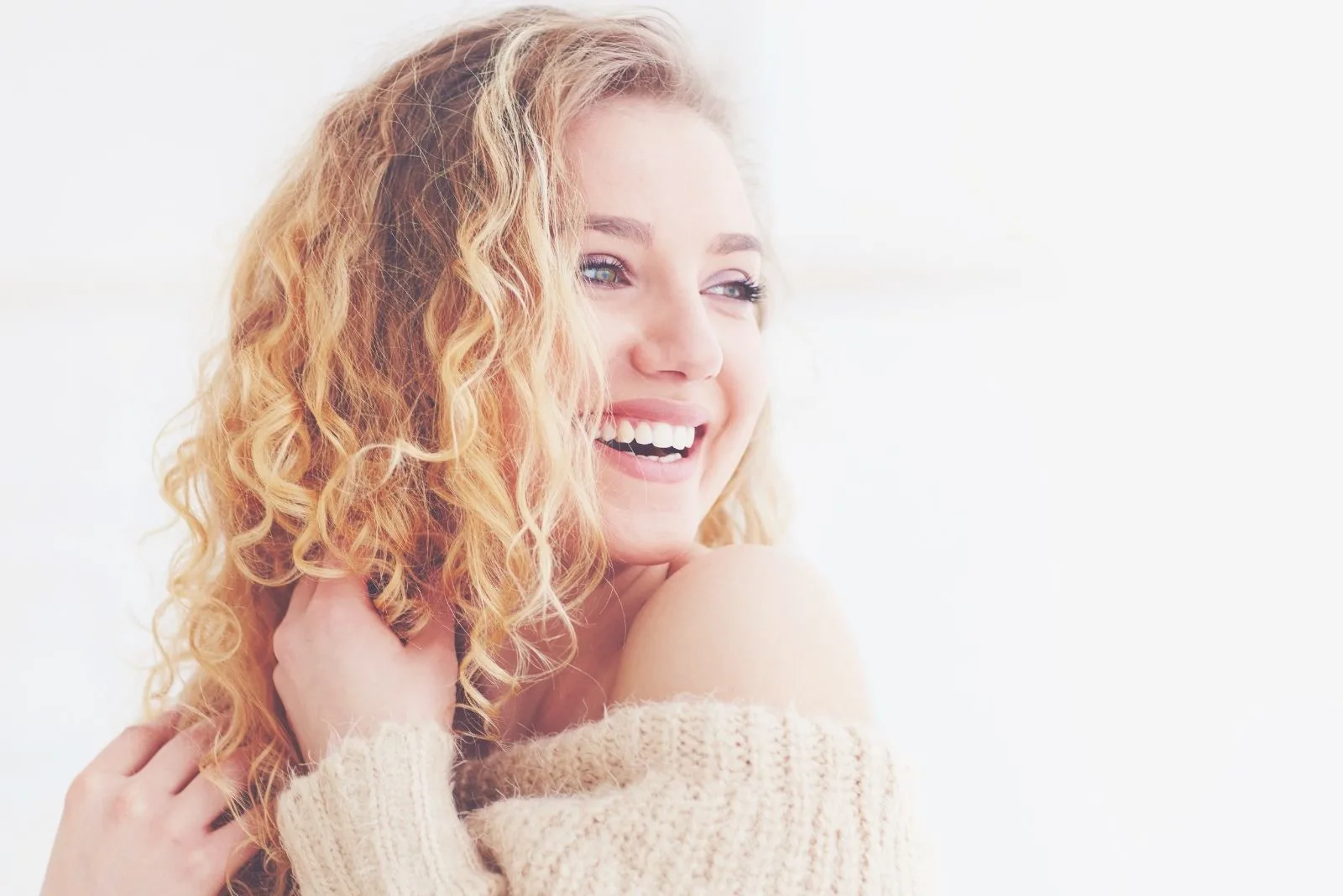 happy beautiful female with cur;ly blonde hair smiling and looking away