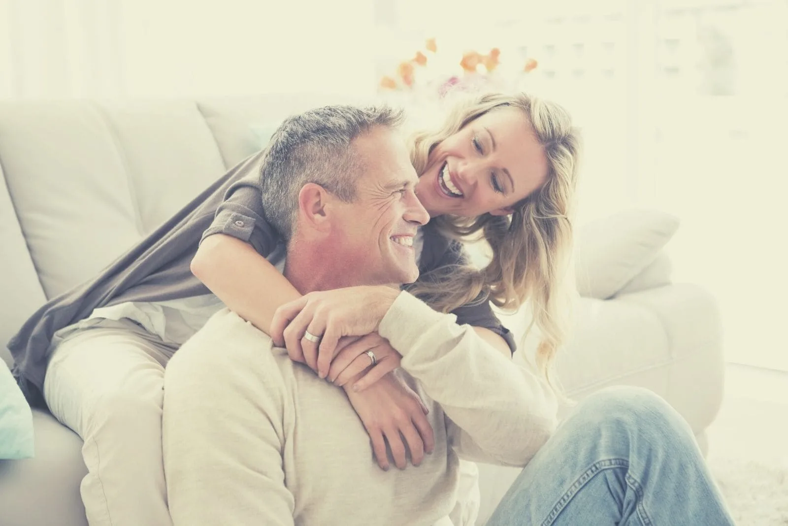 happy couple cuddling in living room while man sitting on the floor