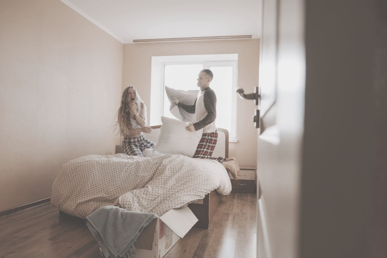 coppia felice che gioca in camera da letto con i cuscini