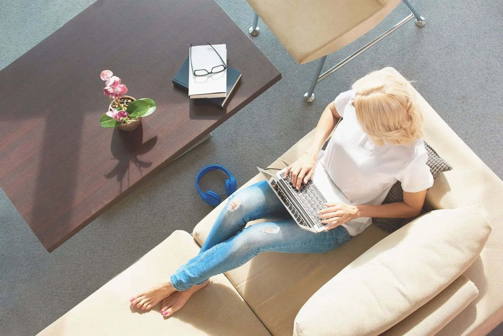 high angle shot of a woman writing on the laptop and sitting on the sofa inside the livingroom