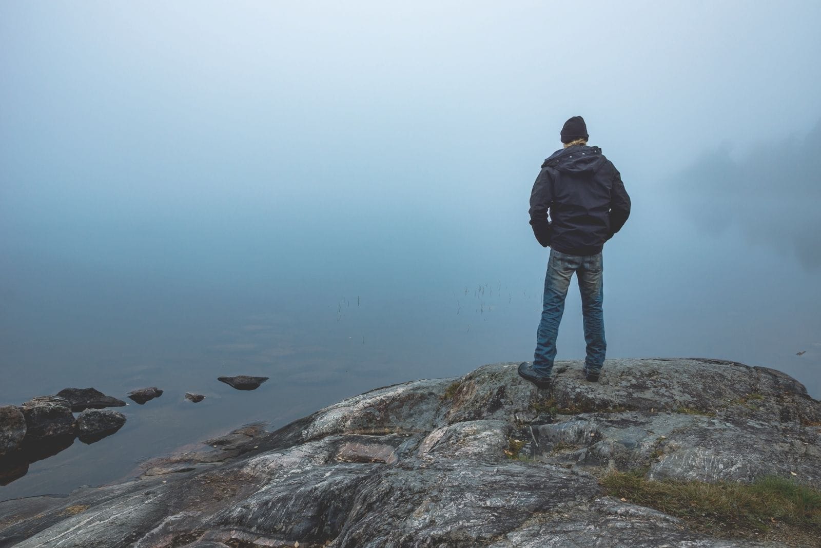 lonely man standing on top of the hill on a foggy afternoon