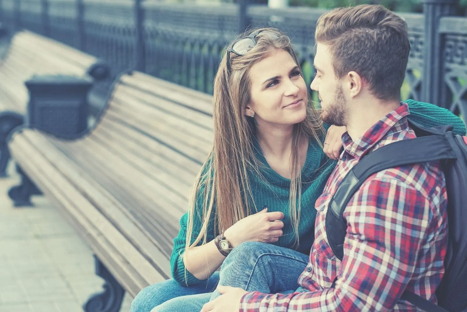 lovely sweet couple sitting in a bench outdoors talking