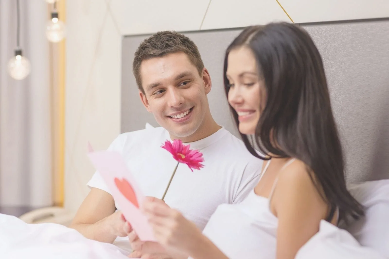 loving couple in bed reading love letter with a flower