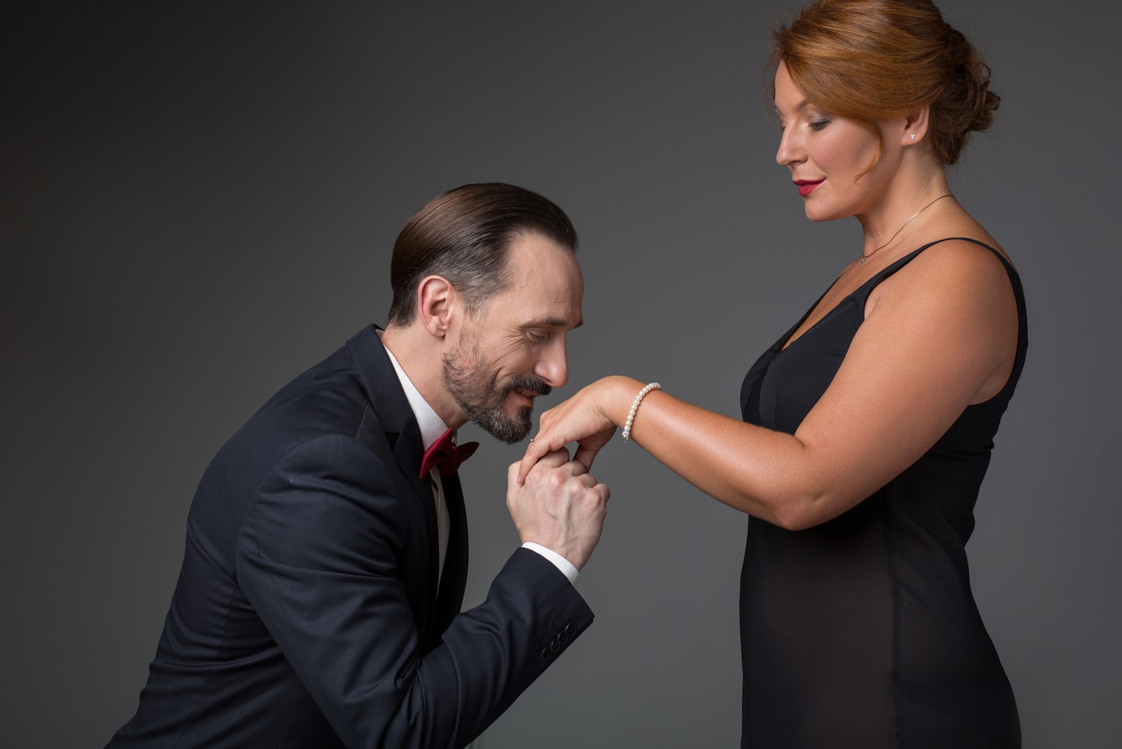 Homem segurando a mão feminina com um anel de ouro e beijando-a.