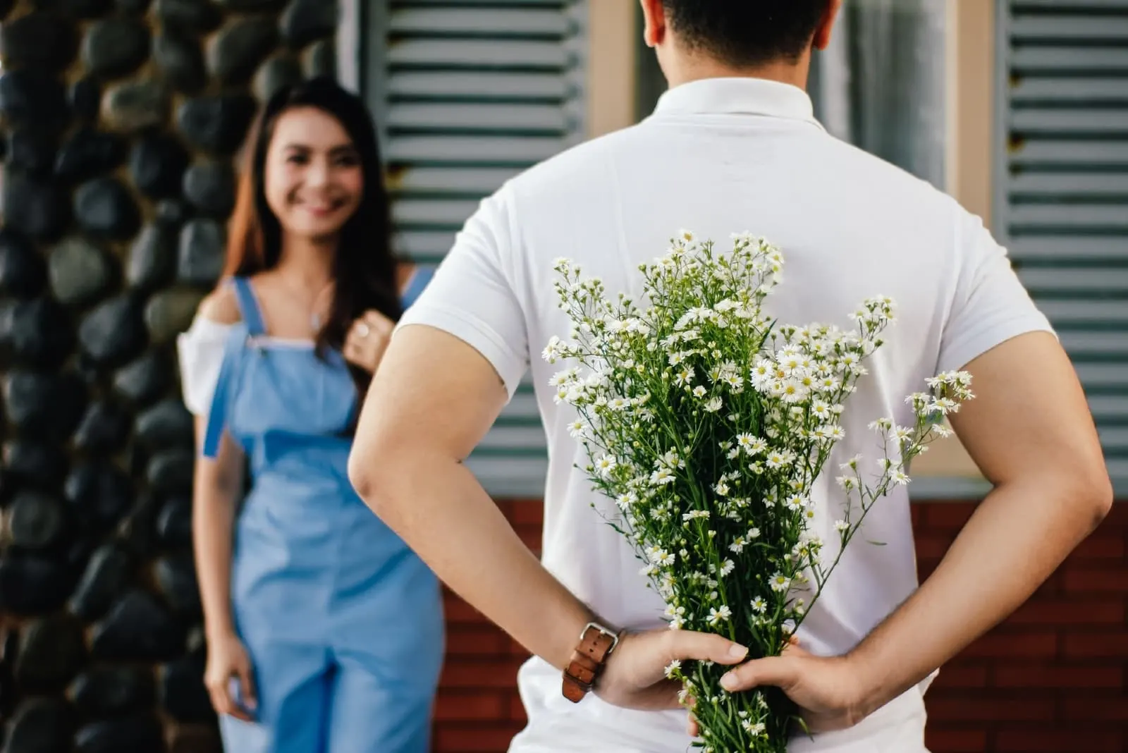 man holding white flowers while standing near happy woman