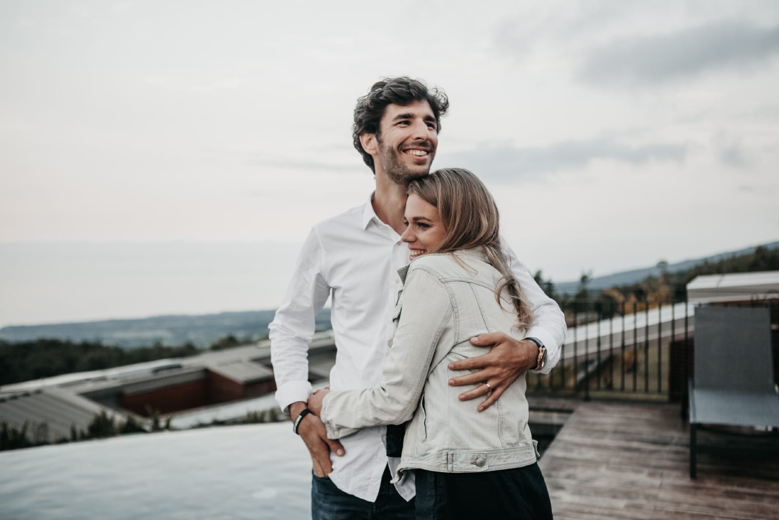 man hugging woman while standing on rooftop