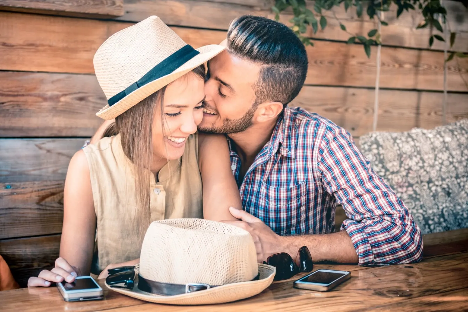 man kissing woman on cheek while sitting in cafe