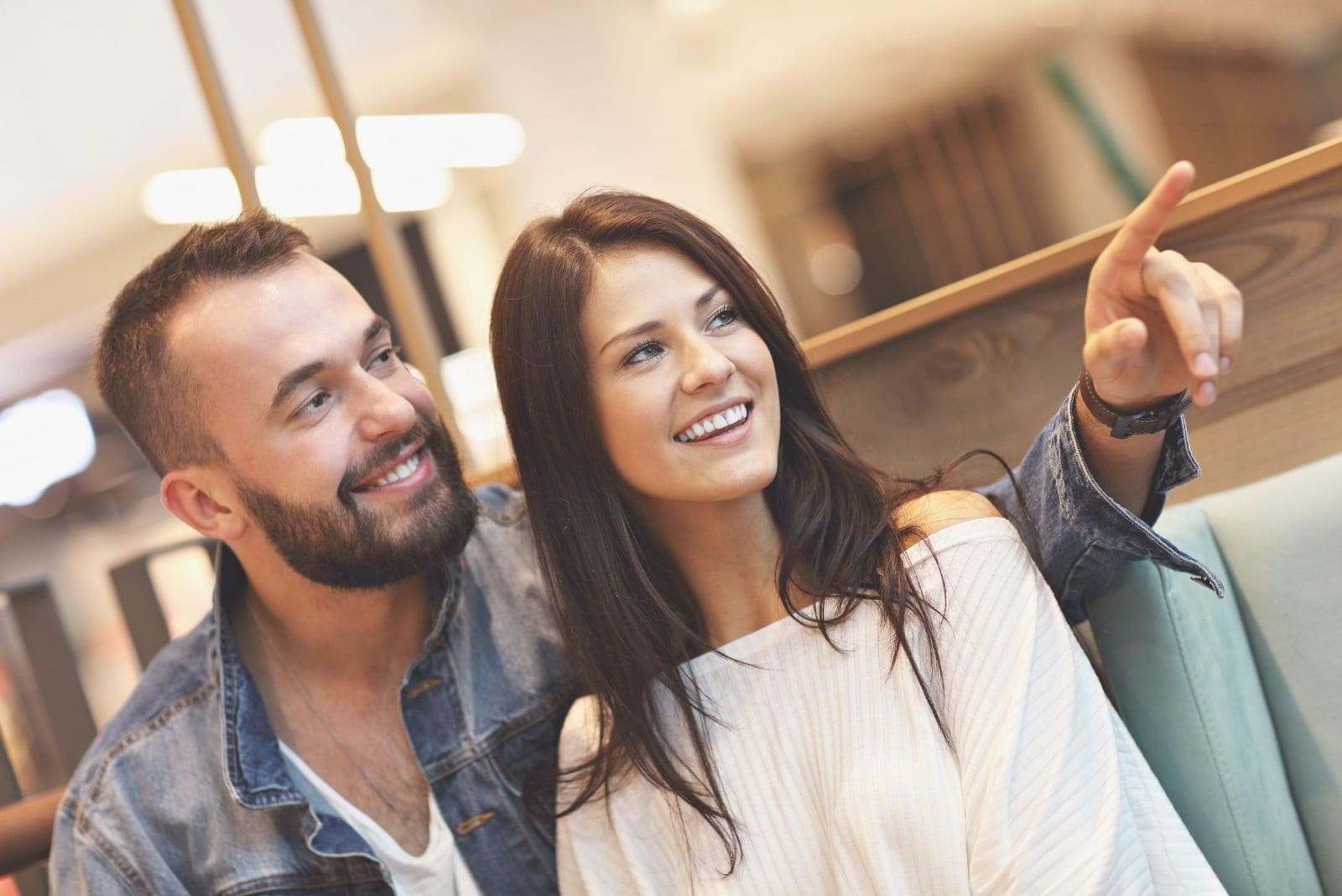 hombre señalando algo mientras sale con su novia en un café interior