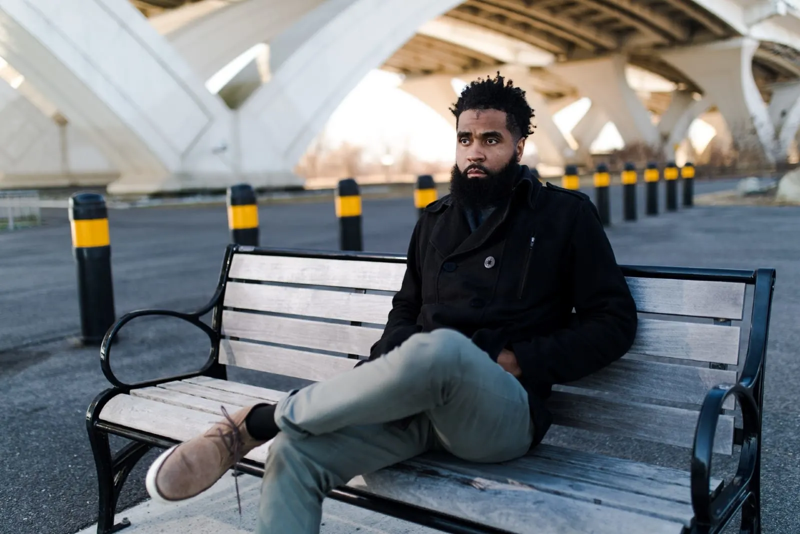 pensive man in black jacket sitting on bench