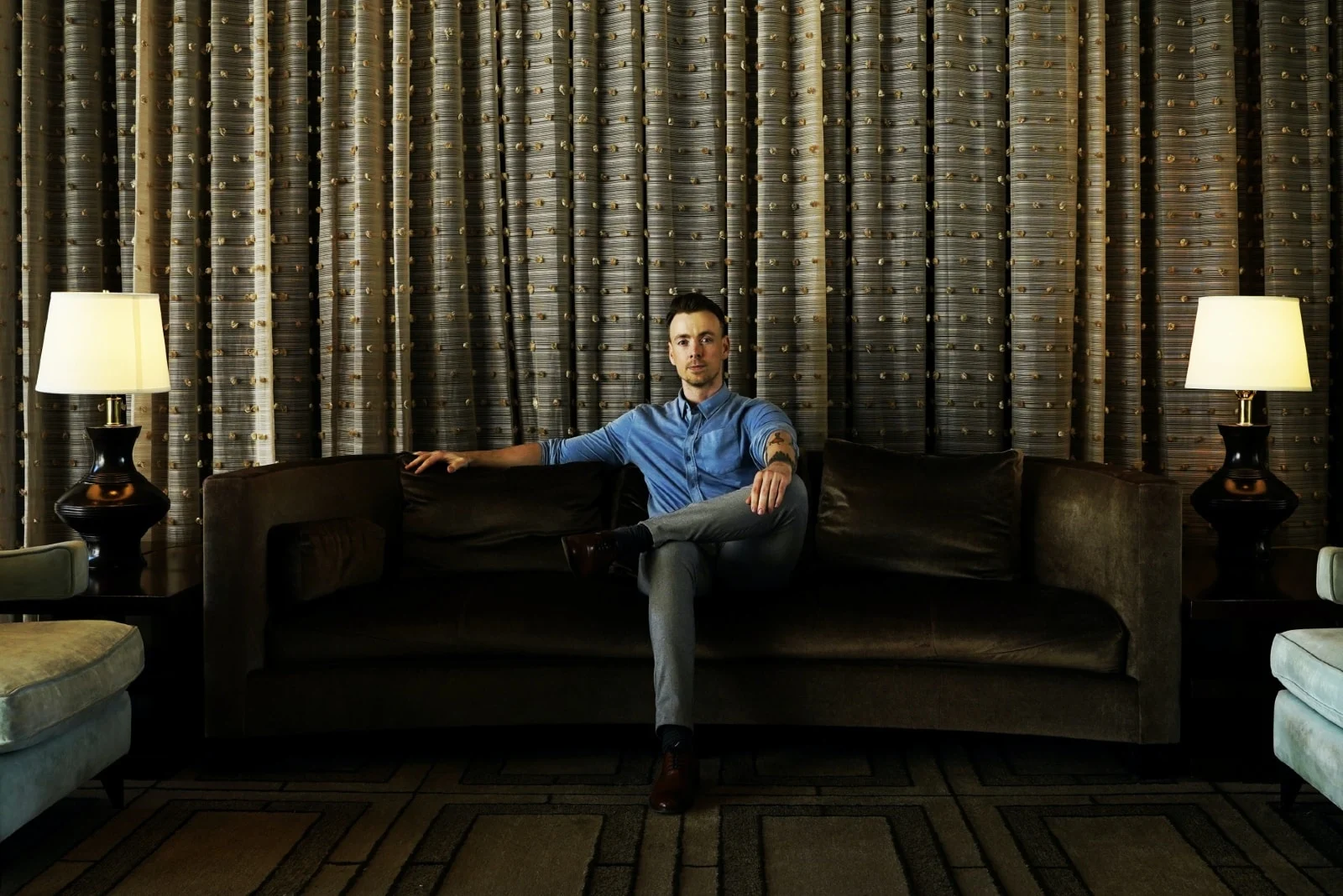 pensive man in denim shirt sitting on couch