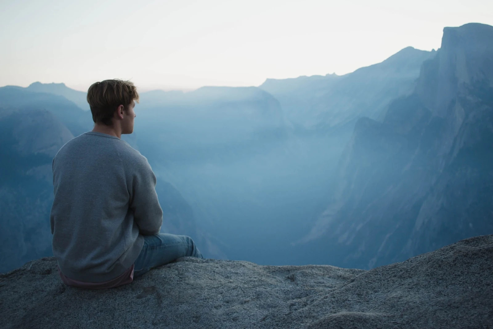 man sitting on rock looking at mountain