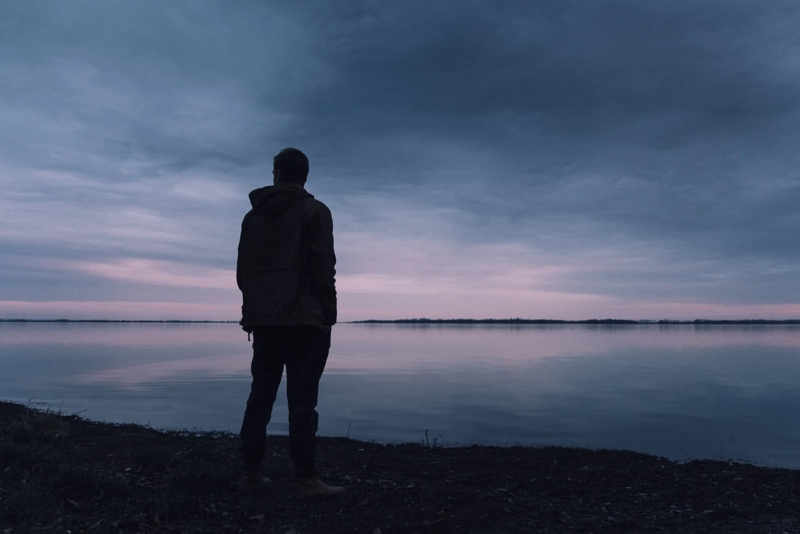 man in gray jacket standing near water