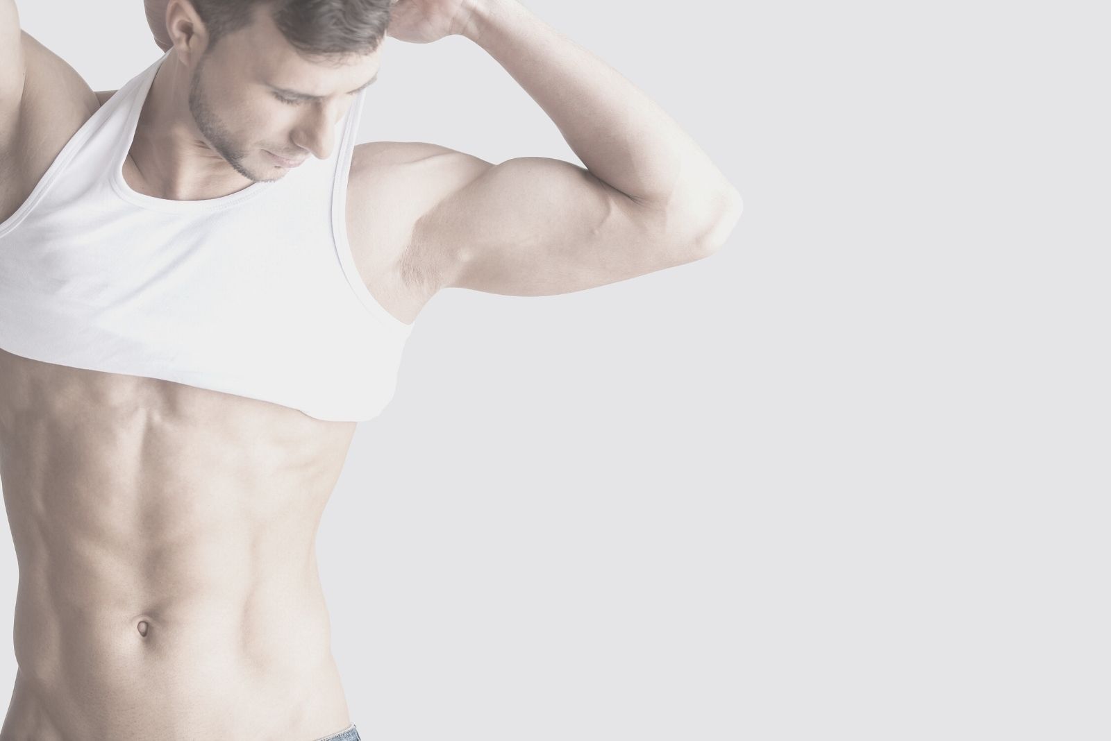 man taking off shirt standing against white wall