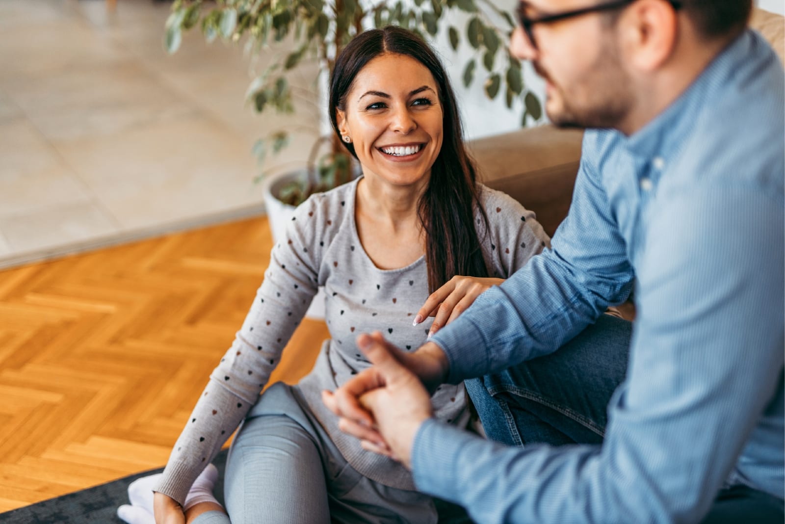 man with eyeglasses talking to woman while sitting indoor