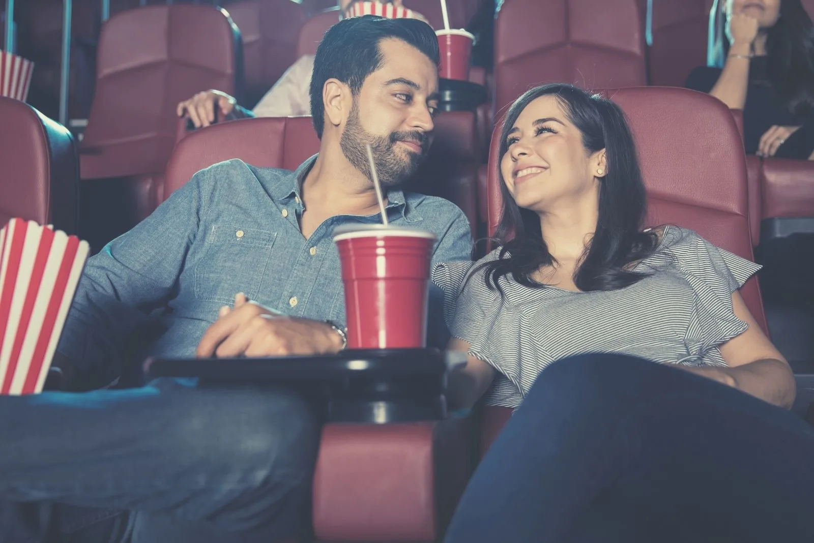 married couple dating watching movies in the moviehouse smiling at each other