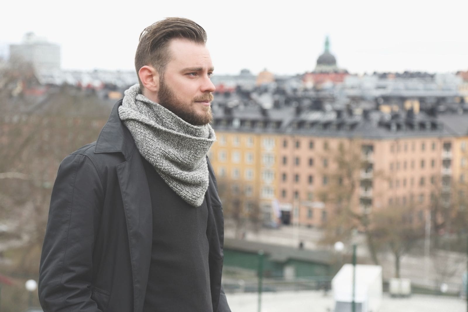 pensive man outdoors standing on a rooftop looking at a far distance