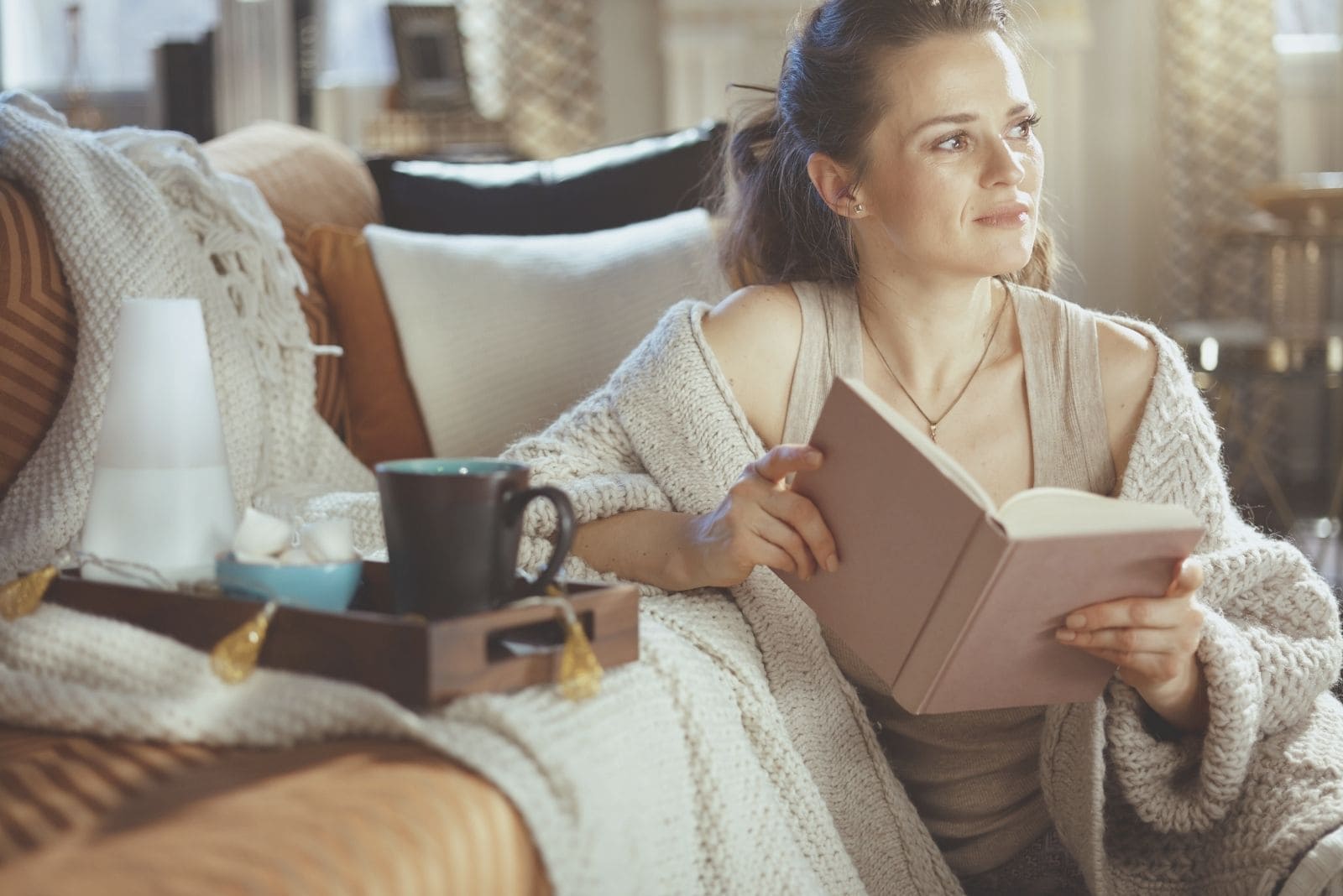pensive woman reading book inside a modern house on a summer/autumn season