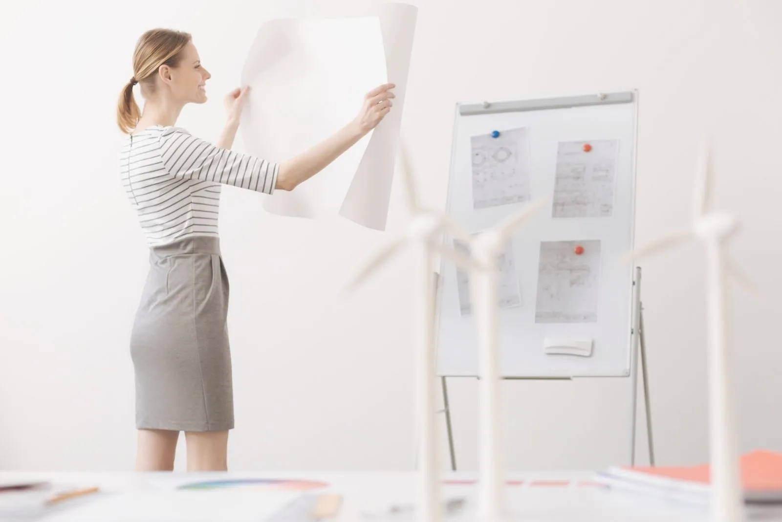 positive female engineer looking and holding a blueprint inside the office