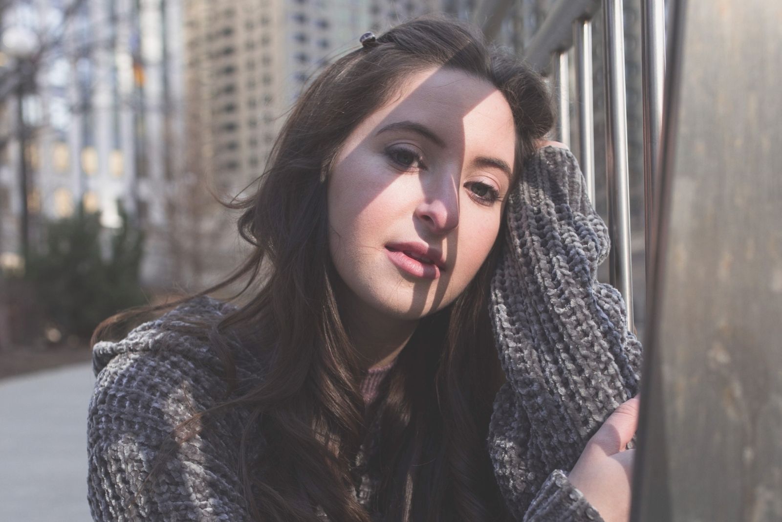 pretty young pensive woman leaning on the railing sitting down beside the railings outdoors