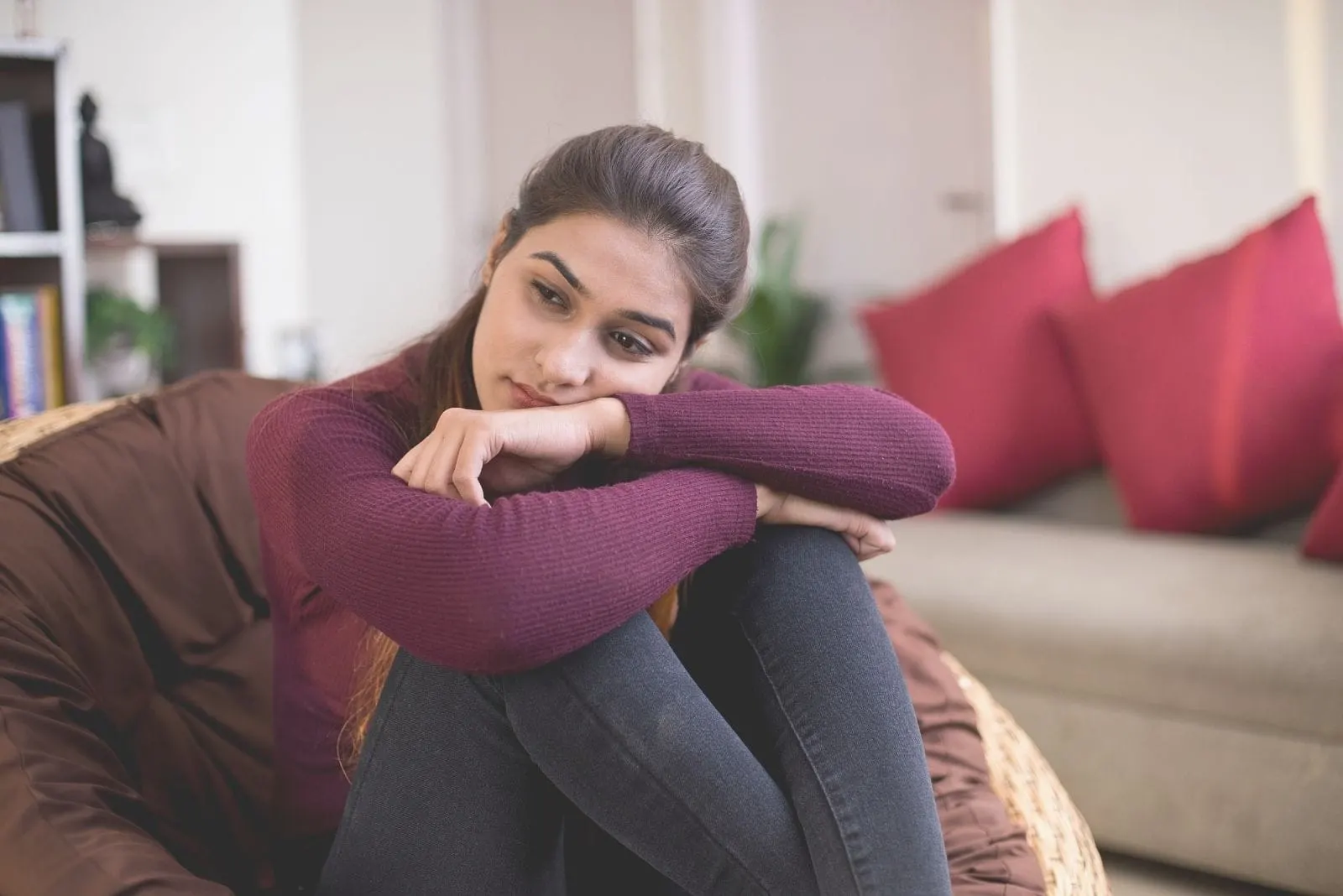 sad depressed woman sitting alone in the sofa inside the living room
