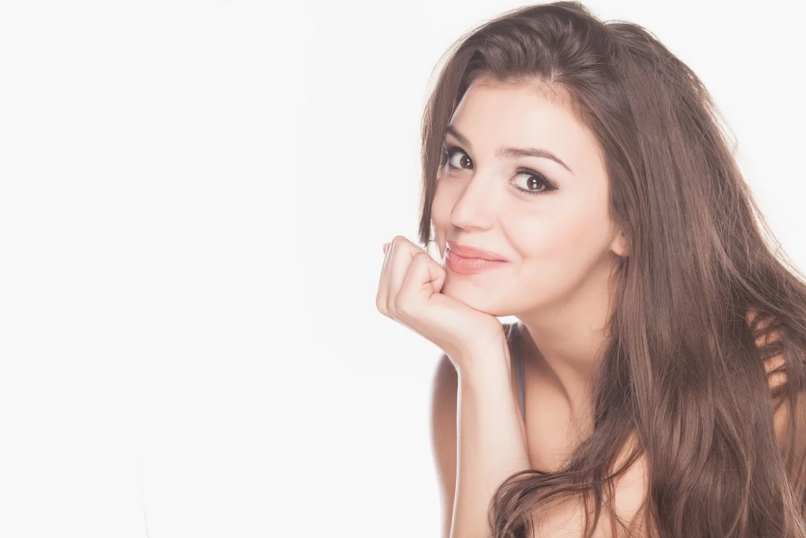 smiling woman on white background with head resting on her hands